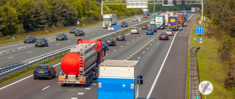 Drukke Nederlandse snelweg met vrachtwagens en personenauto's op meerdere rijstroken richting Duitse grens, illustratief voor verwachte files tijdens het Hemelvaartsweekend 2026.