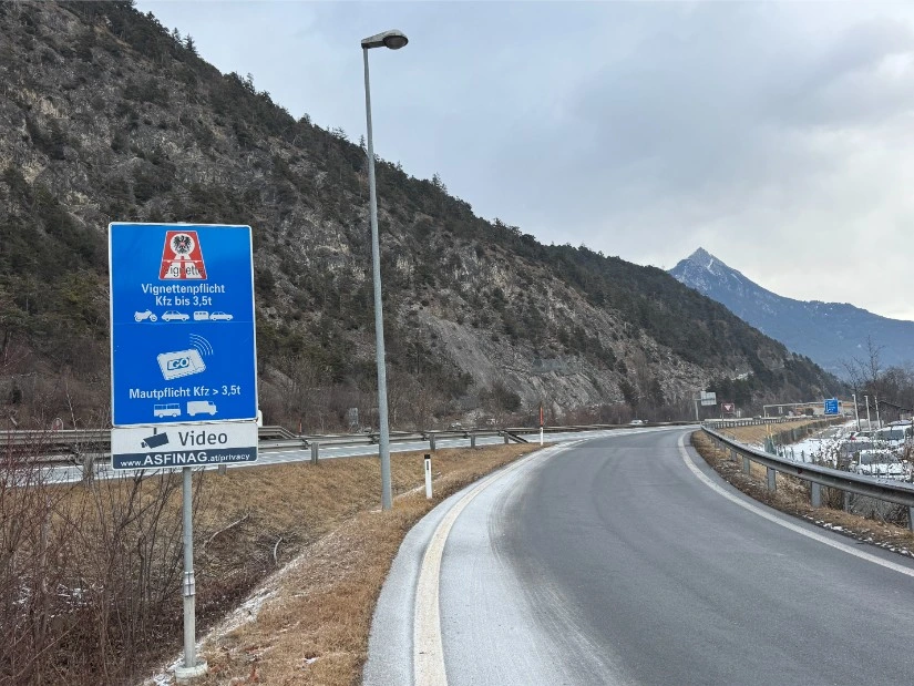 Oostenrijks verkeersbord Vignettenpflicht voor voertuigen tot 3,5 ton en GO-box mautpflicht voor vrachtwagens, met ASFINAG videocontrole-aanduiding en Alpen op de achtergrond, gefotografeerd door Wegenvignetten.nl